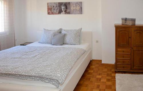 a bedroom with a white bed and a wooden dresser at Stunning Apartment In Senj With Wifi in Senj