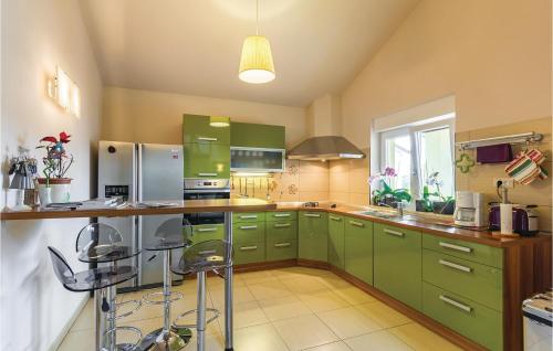 una cocina con armarios verdes y una barra con taburetes en Cozy Home In Medulin With Kitchen, en Medulin