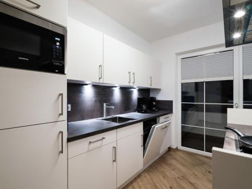 eine Küche mit weißen Schränken und schwarzen Geräten in der Unterkunft Apartment in St Johann im Pongau with sauna in Alpendorf
