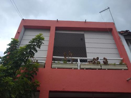 a red building with a window with plants on it at Casa de praia em Itanhaem in Itanhaém