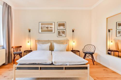 a bedroom with a large white bed with two chairs at Ferienwohnung an der Brunnenaue in Stralsund