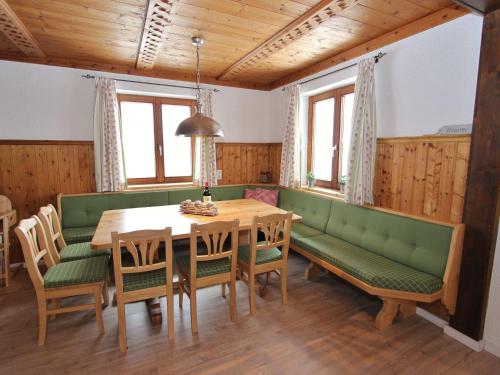 a dining room with a wooden table and green benches at Charming Chalet near Gro arl with Garden in Grossarl