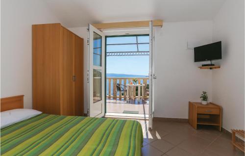 a bedroom with a bed and a balcony with a television at Cozy Apartment In Omis With House Sea View in Zakučac