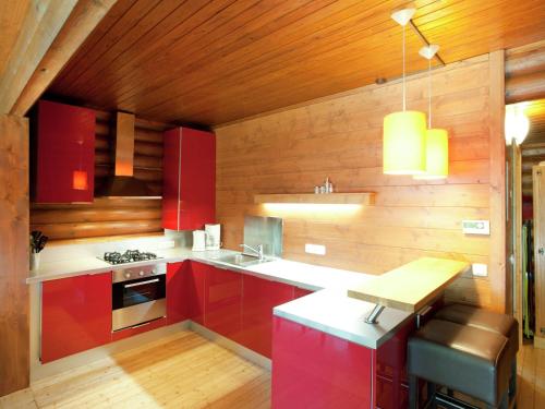 バート・ヘーリングにあるSpacious Chalet near Ski Slopes in Worglの木製の天井のキッチン(赤いキャビネット付)