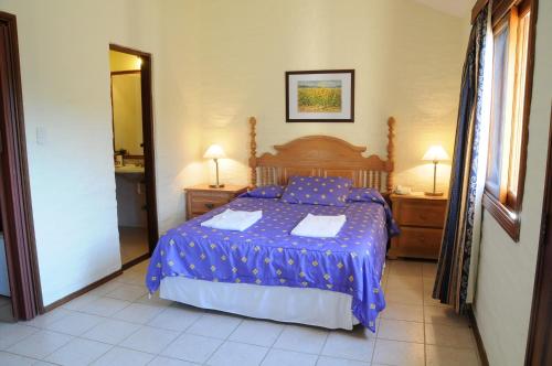 a bedroom with a bed with a blue comforter at Arapey Oasis Termal Hotel in Termas del Arapey