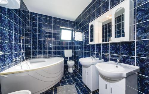 a blue tiled bathroom with a tub and two sinks at Cozy Apartment In Privlaka With House Sea View in Privlaka