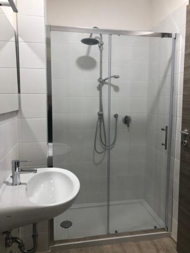 una ducha con una puerta de cristal junto a un lavabo en White, en Terni
