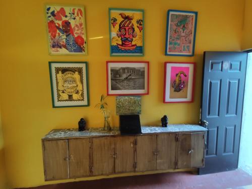 a room with a yellow wall with pictures on the wall at Chuchumbé Hotel & Hostal in Veracruz