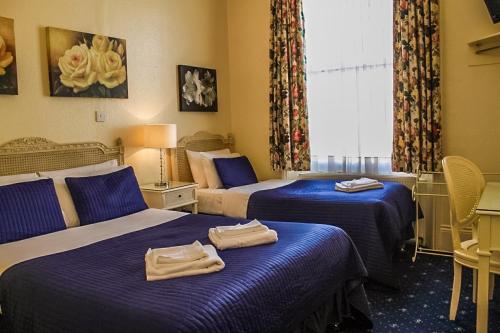 um quarto de hotel com duas camas com toalhas em Blades Hotel em Londres