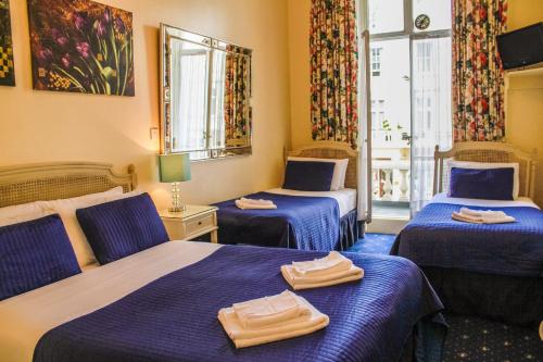 um quarto de hotel com duas camas com lençóis azuis em Blades Hotel em Londres
