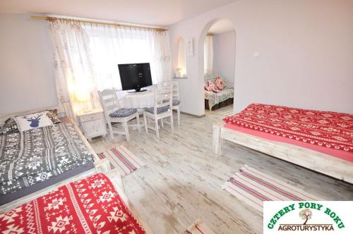 a room with two beds and a desk with a television at Cztery Pory Roku in Jeżów Sudecki