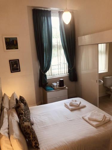 a bedroom with a large white bed with a window at The Purple Tree Guest House in Torquay