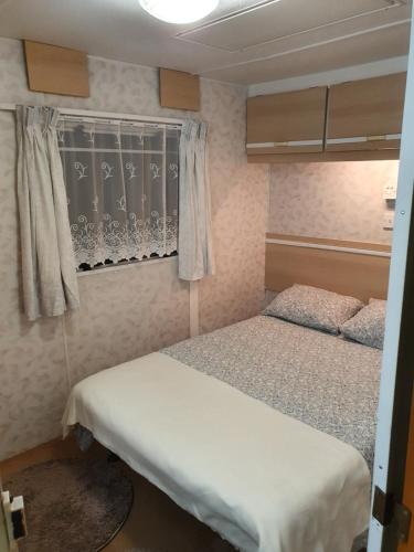 a small bedroom with two beds and a window at Bałtyckie Zacisze - Domki holenderskie w Bobolinie, ul Darlowska 11a in Dąbki