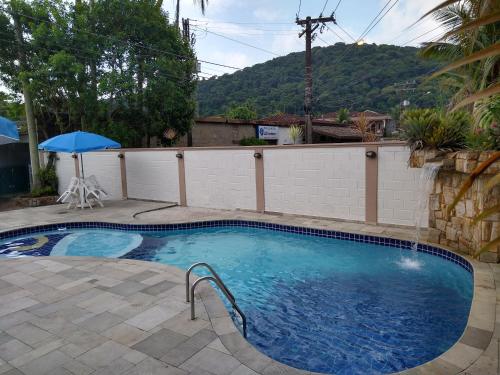 a swimming pool with an umbrella in a yard at Pousada Albamar Guarujá in Guarujá