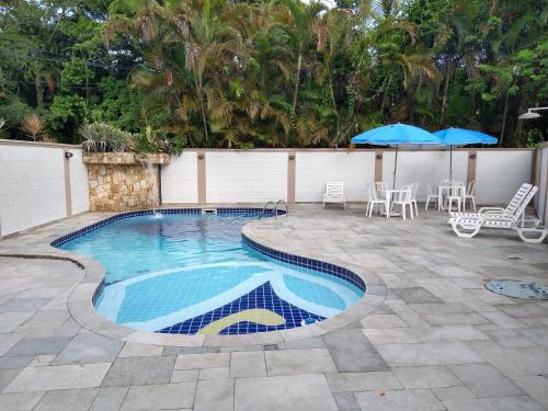 a swimming pool with chairs and umbrellas on a patio at Pousada Albamar Guarujá in Guarujá