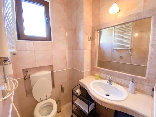 a bathroom with a toilet and a sink and a window at Apartments and Rooms Levantin Inn in Sveti Stefan