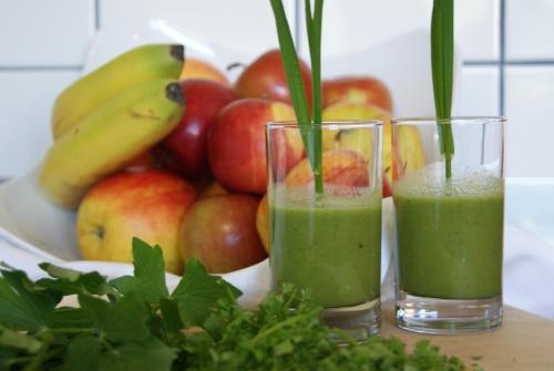 two glasses of green smoothies next to a bowl of fruit at Biohof Naturzeit Faaker See in Drobollach am Faakersee