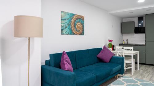 a living room with a blue couch and purple pillows at Sea View Apartments Olimp - Avenue Hotels in Olimp