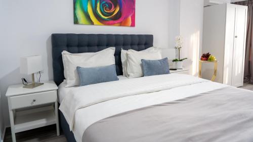 a bedroom with a large bed with a blue headboard at Sea View Apartments Olimp - Avenue Hotels in Olimp