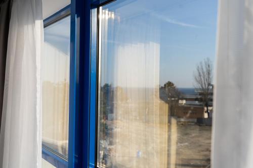a blue window with a view of a yard at Sea View Apartments Olimp - Avenue Hotels in Olimp