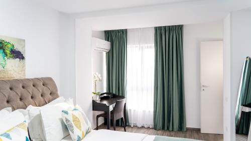 a bedroom with a bed and a window with green curtains at Sea View Apartments Olimp - Avenue Hotels in Olimp