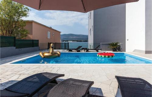 a swimming pool with two chairs and an umbrella at Nine-Bedroom Holiday Home In Arbanija in Trogir