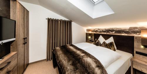 a bedroom with a large bed and a television at Apartments Villa Gardena - Gardenahotels in Selva di Val Gardena