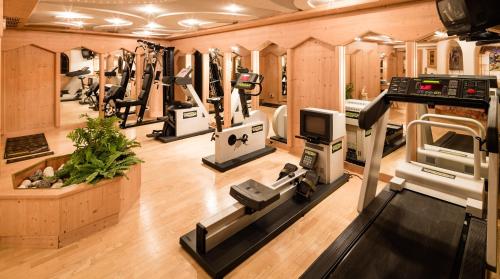 einen Fitnessraum mit mehreren Laufbändern und Maschinen darin in der Unterkunft Apartments Villa Gardena - Gardenahotels in Wolkenstein in Gröden