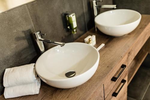 a bathroom with two white sinks on a wooden counter at Apartments Villa Gardena - Gardenahotels in Selva di Val Gardena