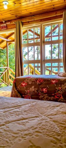 a bed in a room with windows and a couch at Hospedaria Kayser Haus in Urubici