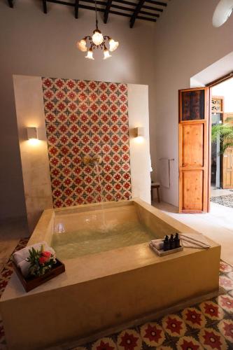 a bath tub in a room with a wall at Casa de Las Palomas Boutique Hotel by Paloma's Hotels - Adults Only in Mérida