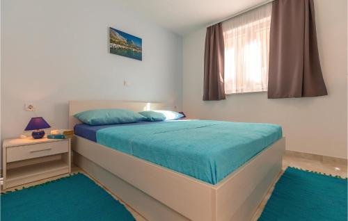 Schlafzimmer mit einem Bett mit blauer Bettwäsche und einem Fenster in der Unterkunft Amazing Apartment In Baska Voda With Wifi in Baška Voda