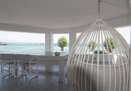 Camera bianca con tavolo e letto a dondolo. di Nautilus Nontas Hotel a Megalochori (Isola di Agistri)