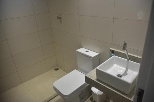 a bathroom with a white toilet and a sink at Casa aconchegante com piscina e muito espaço verde in Aracaju