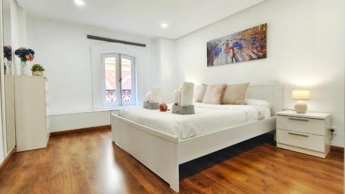 a bedroom with a white bed and a painting on the wall at Hola Madrid Alojamiento Temporal in Madrid