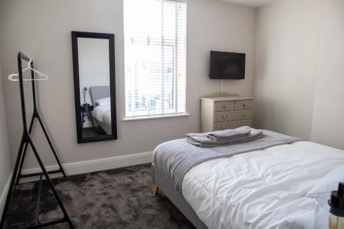 1 dormitorio con cama, espejo y tocador en Withnell Stays - Apartment Two, en Blackpool