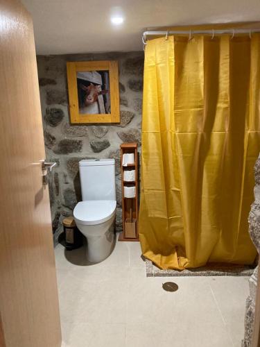 a bathroom with a toilet and a yellow shower curtain at BezerreiraComVida-O refúgio do monte in Bezerreira