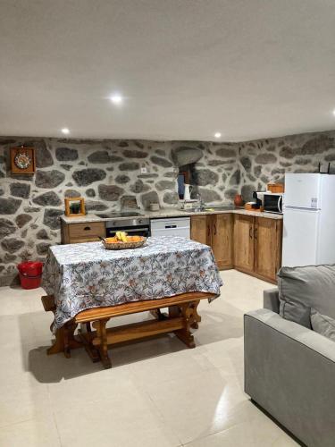 a kitchen with a table and a stone wall at BezerreiraComVida-O refúgio do monte in Bezerreira