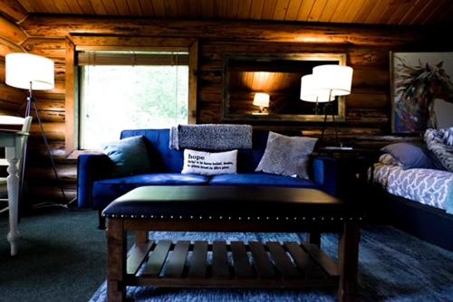 a living room with a blue couch and a bed at Hope Alaska's Bear Creek Lodge in Hope
