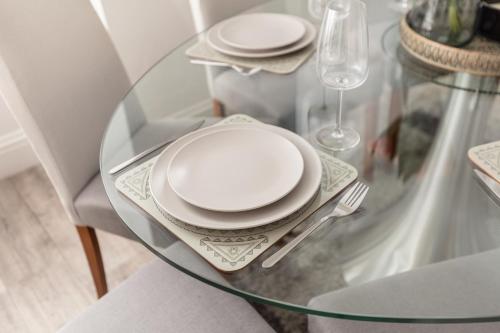 een glazen tafel met witte platen en een vork en mes bij Portland Place in Bath in Bath