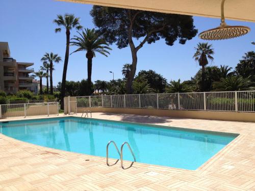 een zwembad in een resort met palmbomen bij Appartement St Raphael in Saint-Raphaël