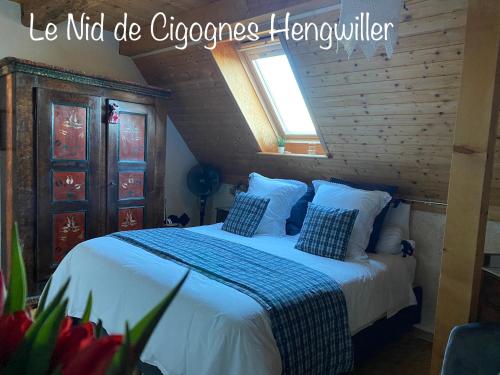 um quarto com uma cama com lençóis brancos e uma janela em Le Nid de Cigognes em Hengwiller