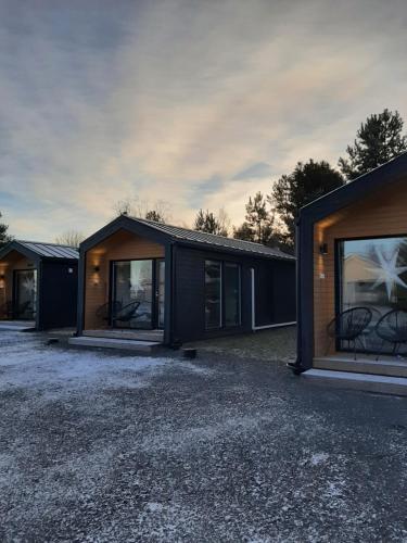 Willa Rauha E في Lumijoki: منزل أسود مع نوافذ كبيرة على ممر