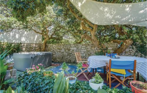 a table and chairs in a garden with trees at Pet Friendly Home In Mali Losinj With Sauna in Mali Lošinj
