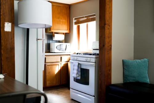 a small kitchen with a stove and a microwave at Hope Alaska's Bear Creek Lodge in Hope