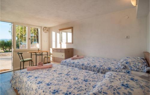 a bedroom with two beds and a table and a window at Lovely Home In Postira With Wifi in Dol