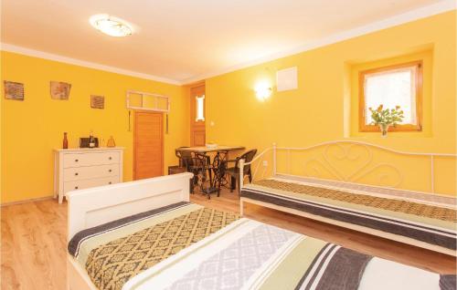 two beds in a room with yellow walls and a table at Gorgeous Apartment In Omisalj With Kitchen in Omišalj