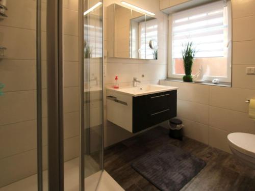 a bathroom with a sink and a glass shower at Ferienhaus mit Garten in Neßmersiel