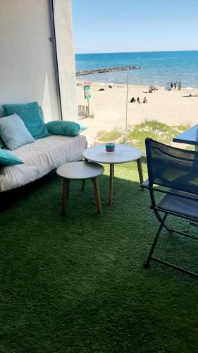 sala de estar con sofá, mesas y la playa en Studio Vue Mer exceptionnelle Première Ligne Carnon plage, en Carnon-Plage