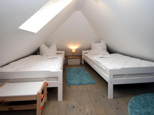2 Betten in einem Dachzimmer mit Fenster in der Unterkunft Semi-detached house Schwittersum, Dornum in Dornum